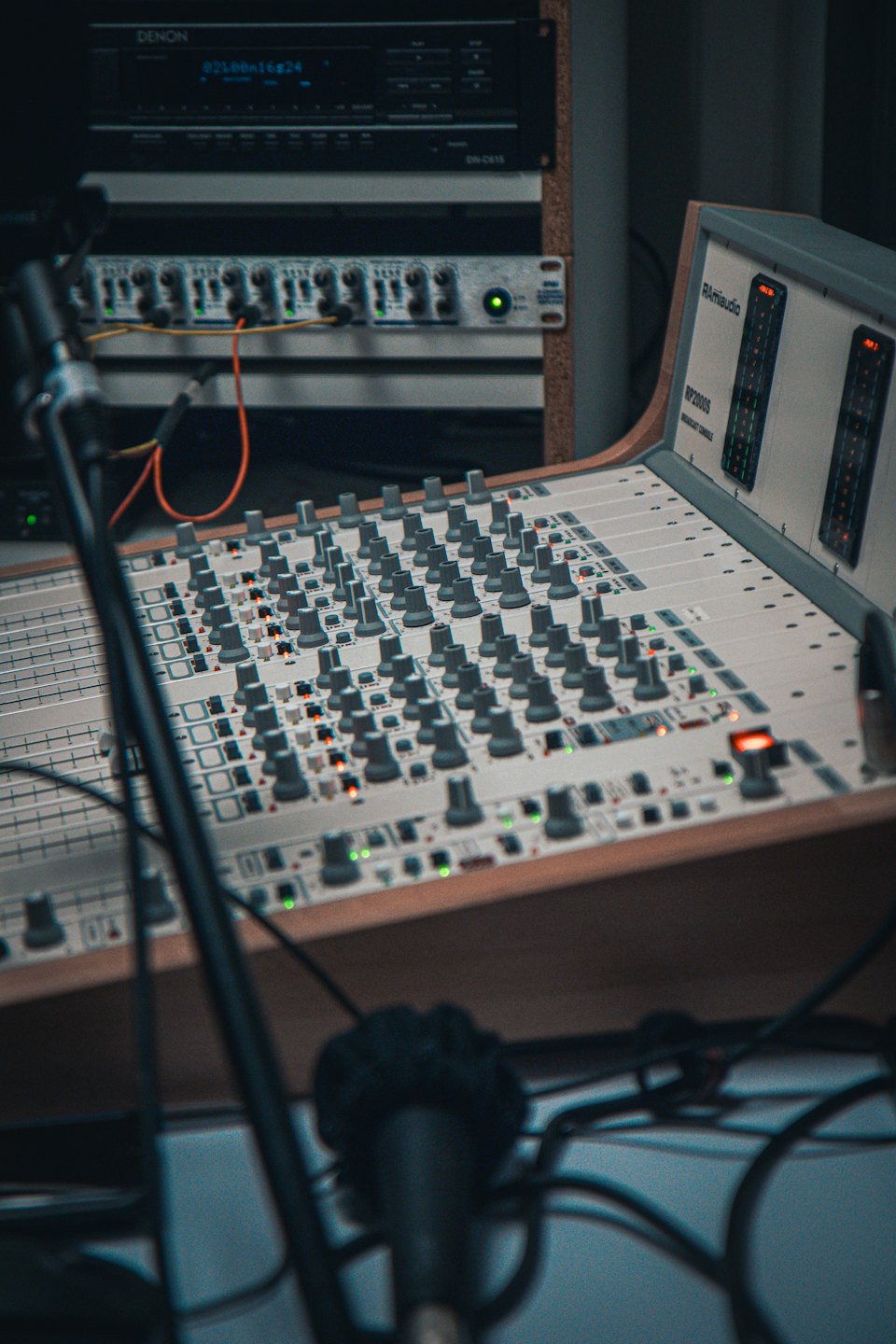 Audio mixing console with faders and illuminated buttons in a studio.