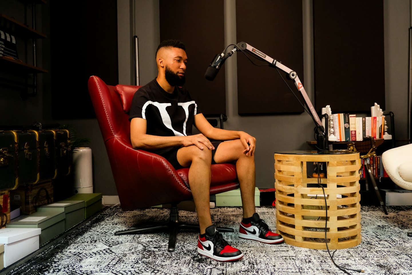 Man sitting in a studio next to a podcast microphone.